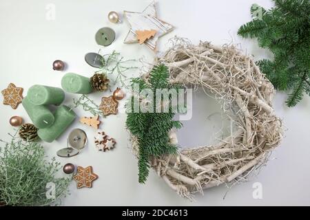 Vorbereitung Dekoration für Weihnachten und Advent Feiertage, Kranz aus gebleichtem Holz, Tannenzweige, Lebkuchengebäck, Ornamente und Kerzen auf einem weißen Stockfoto