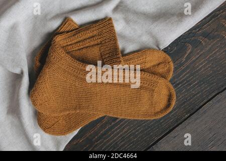 Ein Paar handgestrickte Socken. Dunkler rustikaler Holzhintergrund. Plase für Text. Stockfoto