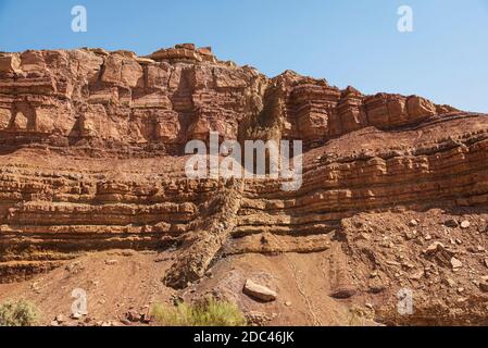 Ein diagonaler magmatischer igneous Deich schneidet durch rot und orange Horizontale Kalkschichten in nahal Ardon im Makhtesch Ramon Krater in Israel Stockfoto