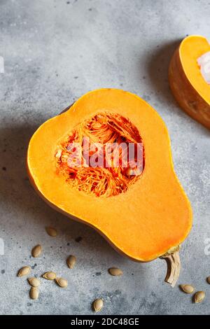 Frischer Butternusskürbis auf grauem Hintergrund. Butternut Kürbis. Hälften von rohem orangefarbenem Kürbis. Kontrastfoto. Gesunde Mahlzeit Prep, Rezept Vorbereitung Stockfoto