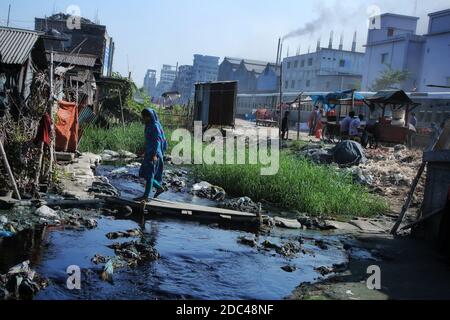 Dhaka, Bangladesch. November 2020. Eine Frau, die mit einem Holzbrett zu ihrem Haus zu betreten, als die Straße mit der Textilmühlen Verschwendung im Shyampur Industriegebiet in Dhaka überflutet wird.die meisten Menschen in diesem Bereich sind Opfer der Verschmutzung durch die Anwesenheit von giftigen Chemikalien geworden, vor allem Färbung Chemikalien. Aufgrund der ungeplanten Kanalisation von Textilfabriken leiden die Bewohner dieses Gebiets lange Zeit. Kredit: SOPA Images Limited/Alamy Live Nachrichten Stockfoto