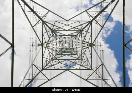 Abstrakte harte Textur aus diesem industriell thematisierten Bild eines elektrischen Pylon-Übertragungsturms. Der Blick in den Himmel, während das Metall zusammenläuft. Stockfoto