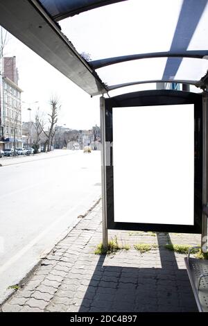 Nahaufnahme des Werbeschilds in der Mitte der Straße. Bushaltestelle am Straßenrand Stockfoto