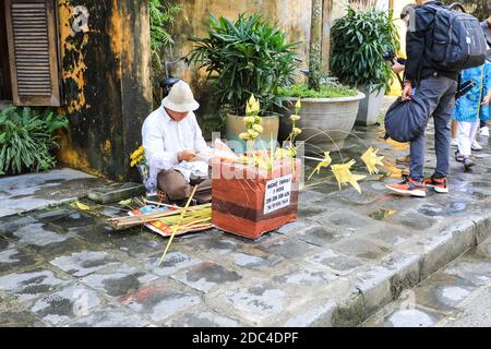 Ein Mann auf der Straße macht Ornamente oder Dekorationen aus getrockneten Blättern, Hoi an, Vietnam, Asien Stockfoto