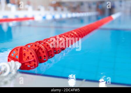Hintergrund - Fragment des Wettkampfpools mit blauem Wasser Und markierte Schwimmbahnen Stockfoto