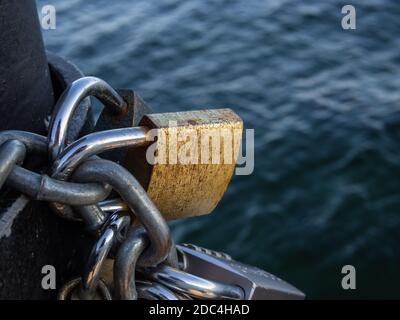 Vorhängeschlösser, die durch eine Kette verbunden sind. Das Konzept der Versklavung. Tag, Nahaufnahme, Details. Stockfoto