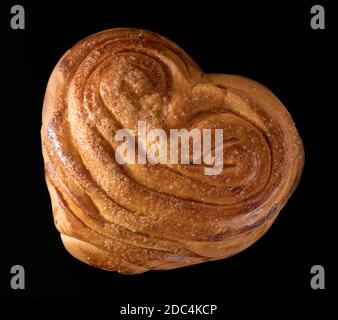 Süßes, rodges, frisch gebackenes Brötchen auf schwarzem Hintergrund Stockfoto