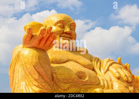 Budai oder Hotei - gott des Reichtums, Fat Buddha mit Geld in der Hand, im Hintergrund des blauen Himmels Stockfoto