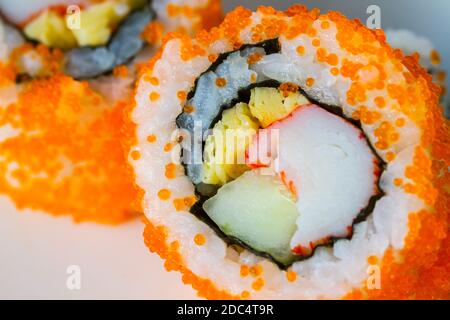 Extreme Nahaufnahme California Maki Sushi mit Masago - Rolle aus Krabbenfleisch, Ei, Gurke innen. Masago (Rochen) draußen, weicher Fokus, mittlerer Fokus Stockfoto