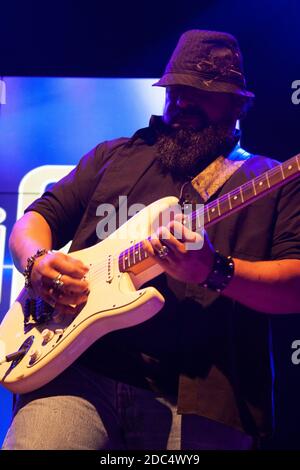 Bärtiger Mann im Hut, der Gitarre spielt und unter Blau Saiten spielt Licht in Mexiko Stadt Stockfoto