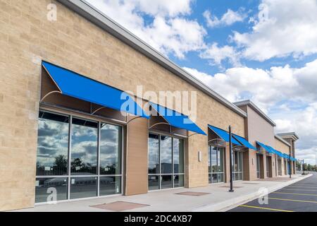 Brandneu, ohne Logo, Beschilderung oder Label-Schaufenster einer im Bau befindlichen Mall in den USA mit blauen Markisen über dem Eingang, blau bewölktem Himmel Ref Stockfoto