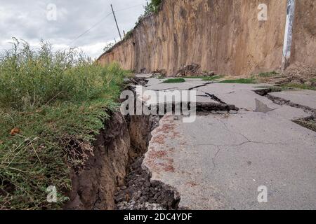 Der zerstörte Weg die Folgen des natürlichen Kataklysmus des Erdrutsches des Bodens, den Asphaltpflaster am Sommertag knacken, niemand. Stockfoto