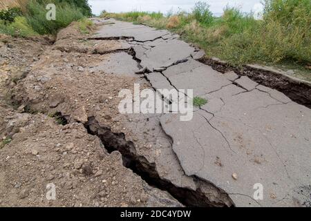 Der zerstörte Weg die Folgen des natürlichen Kataklysmus des Erdrutsches des Bodens, den Asphaltpflaster am Sommertag knacken, niemand. Stockfoto