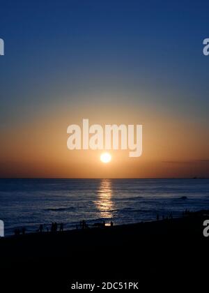 Leute, die an einem Florida Golfküstenstrand nahe Destin und South Walton County, Florida USA, bei Sonnenuntergang spazieren gehen. Stockfoto