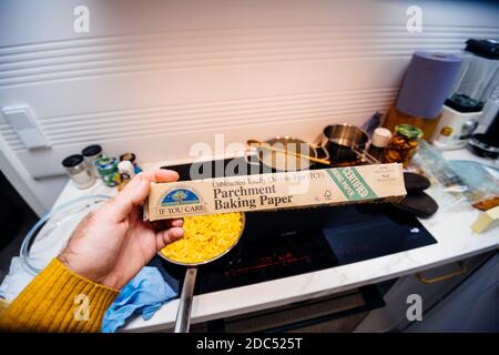 Paris, Frankreich - Nov 11, 2020: Pov männliche Hand hält vor Küchenhintergrund neu Pergament Backpapier hergestellt von If you are totally chlorid-free Stockfoto