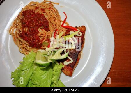 Spaghetti-Menü mit traditionellen javanischen Rawon-Gewürzen sowie gegrilltem Meeresfisch und Gemüse Stockfoto