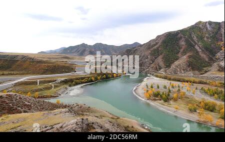 Der Zusammenfluss zweier türkisfarbener Gebirgsflüsse in einem malerischen Tal am Fuße hoher Hügel. Zusammenfluss von Tschuja und Katun, Altai, Sibirien, Russ Stockfoto