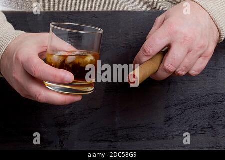 Herrenhände mit einer Zigarre und einem Glas Whiskey Stockfoto