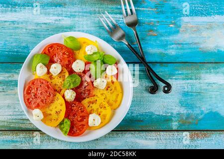 Farbenfroher Salat aus Tomaten, Mozzarella und Basilikum mit Gabel. Draufsicht. Stockfoto