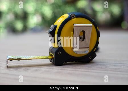 Gelbes Maßband auf Holzbrett bei verschwommenem Hintergrund Stockfoto