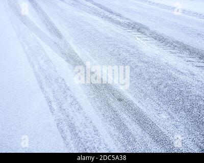 Straße im Winter. Asphalt mit Schnee bedeckt und Abdrücke von Reifenspuren Stockfoto