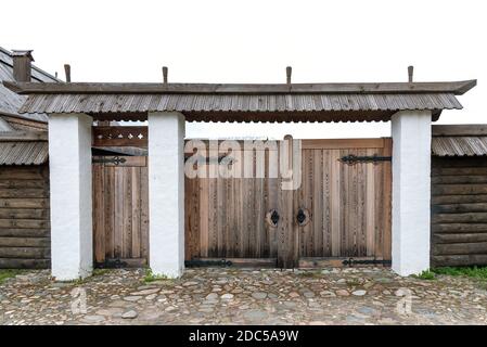 Verwittertes Tor mit grünem Dach und Zaun in der Nähe von ländlichen Haus Stockfoto