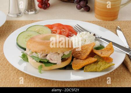 Ein Thunfisch-Sandwich auf einem Bagel mit Tomaten, Quark und gebratenen Tortilla-Chips Stockfoto