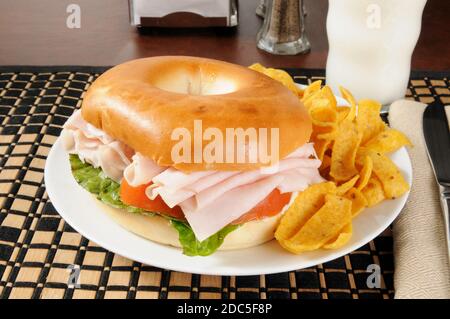 Ein Schinken-Sandwich auf einem Bagel mit einem Glas Milch Stockfoto