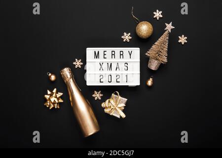 Lightbox mit Text MERRY XMAS 2021 und goldenem weihnachtsdekor auf schwarzem Hintergrund. Kreatives Layout in monochromen Farben Stockfoto