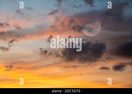 Ein Vollmond steigt in einem bunten Sonnenuntergang Himmel Stockfoto