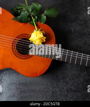 Leichte Akustikgitarre und gelbe Rose. Schöner romantischer Hintergrund. Stockfoto