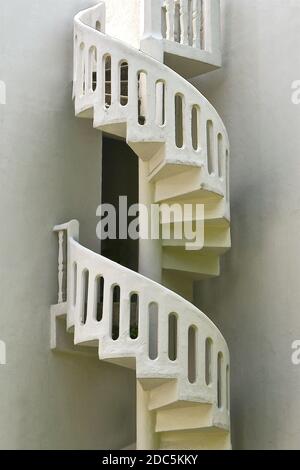 Eine externe Steinspiraltreppe in der Ecke eines weißen Gebäudes. Stockfoto