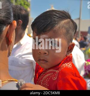 Nahaufnahme Porträt eines kleinen hindu-Jungen mit einem weißen Bindi, in einer Parade von seiner Mutter getragen. Stockfoto