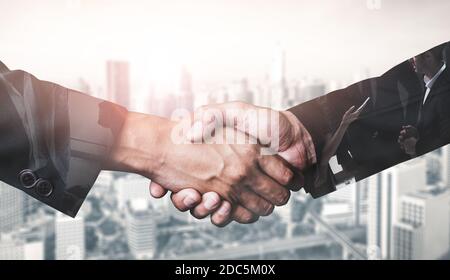 Doppelbelichtung Bild von Geschäftsleuten Handshake auf Stadt Bürogebäude im Hintergrund zeigt Partnerschaft Erfolg des Geschäfts. Konzept von Stockfoto
