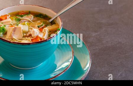 Eine Schüssel frisch gekochte Hühnernudelsuppe mit Löffel Isoliert auf einem Tisch Stockfoto