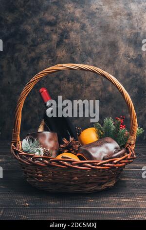 Flasche Rotwein im Weihnachts-Geschenkkorb. Glühwein mit Orangen, Tassen und Tannenbaumschmuck in Box. Draufsicht Stockfoto