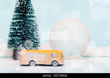 Miniatur gelben Bus und Tannenbaum während Schneefall, Weihnachts-Postkarte mit Platz für Text Stockfoto