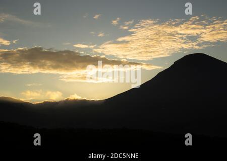 wolkiger Himmel über dem Berg Sindoro. Schwarze Wolken mit morgendlicher Sonneneinstrahlung Stockfoto