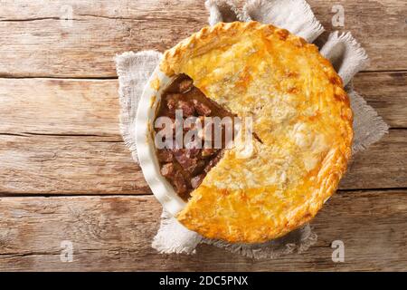 English Beef Steak Pie mit knusprigem Blätterteig close-up in einer Backform auf dem Tisch. Horizontale Ansicht von oben Stockfoto