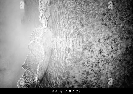 Luftdrohne schießen von oben schwarzen Sandstrand. Natur Textur, monochromer Prozess, Strandlandschaft, tropisches Muster Stockfoto