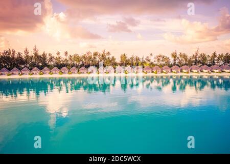 Wunderschöner farbenprächtiger Sonnenuntergang auf der tropischen Insel auf den Malediven im Indischen Ozean. Luxuriöse Strandvillen mit Palmen. Erstaunliche Sommerziel szenische Entspannung Stockfoto