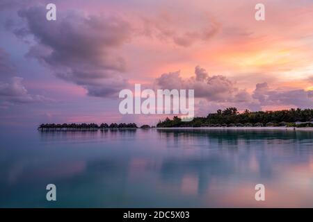 Über Wasser Bungalows mit erstaunlichen Lagune Reflexion. Bunte Himmel Wolken über tropischen Insel. Sommerparadies, luxuriöse Landschaft. Landschaftlich reizvoller Ort Stockfoto
