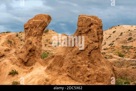 Märchenhafte Schlucht am Issyk-kul-See in Kirgisistan mit roten Bergen und dunklem Regenhimmel. Stockfoto