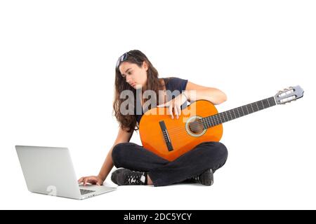 Fröhliches Mädchen posiert mit Gitarre und Laptop, isoliert in Weiß Stockfoto