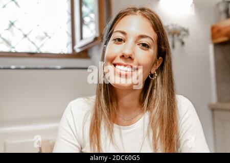 Zuversichtlich junge schöne Frau lächelnd Blick auf die Kamera für Eine Videokonferenz zu Hause - Porträt von Eine niedliche lange Haare weiblich allein pers Stockfoto