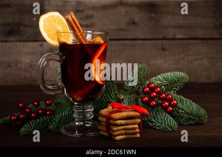 Glühwein mit Zimt-Sticks orange Tannenzweig und Kugeln Weihnachtskomposition auf dunklem Holzhintergrund Stockfoto