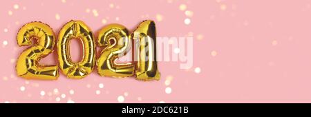 Banner mit 2021 aus goldenen Ballons mit glänzendem Bokeh. Festliche Komposition mit Platz für Text auf einem rosa pastellfarbenen Hintergrund. Stockfoto