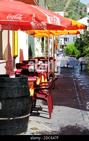 Blick entlang einer traditionellen spanischen Dorfstraße mit Restaurants im Freien, Benahavis, Spanien. Stockfoto