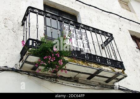 Schmiedeeiserner Balkon und Fenster mit zum Verkauf Zeichen auf einem Stadthaus in der Altstadt, Casares, Spanien. Stockfoto