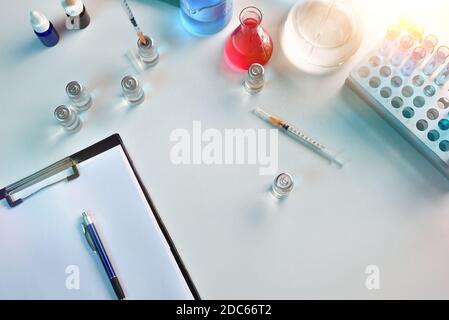 Einwegspritze auf einem Tisch mit Fläschchen und Glaswaren in einem pharmazeutischen Labor. Draufsicht. Horizontale Zusammensetzung. Stockfoto